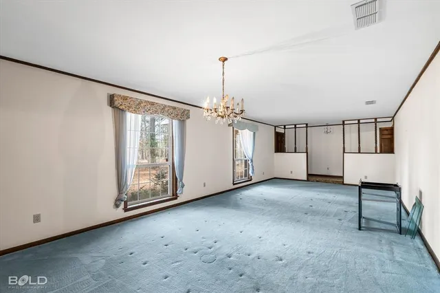 an empty room with chandelier fan and windows