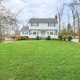 a view of a house with a big yard and large trees