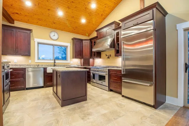 a kitchen with stainless steel appliances granite countertop a stove a sink and a refrigerator