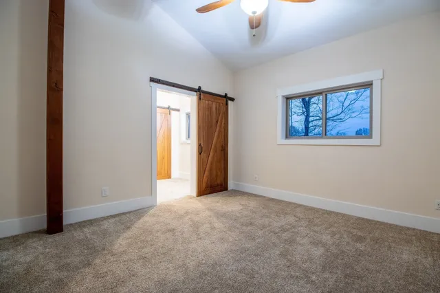 an empty room with a chandelier fan and windows
