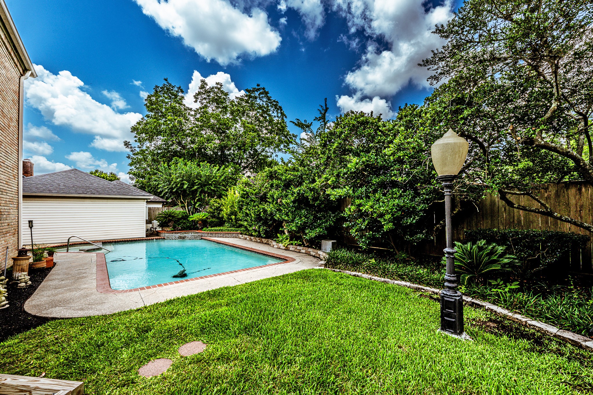 6047 Spring Creek Lane Spring, TX 77379 - Photo 44 of 50 Nestled beneath mature shade trees, the pool area offers a peaceful setting for slow afternoons, weekend gatherings, and cooling off during long Texas summers. With its courtyard inspired layout and timeless surroundings, the backyard feels designed for making memories season after season.