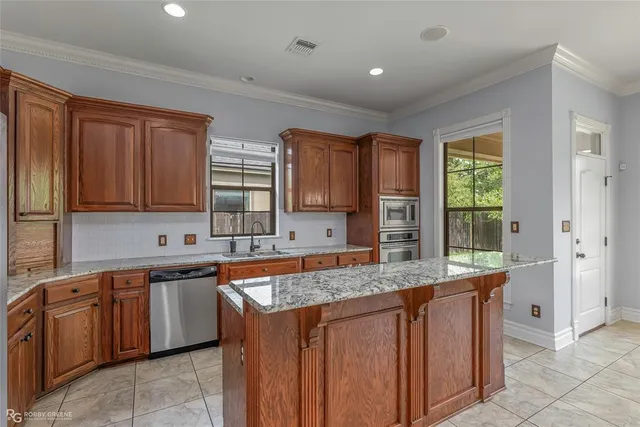 a kitchen with stainless steel appliances granite countertop wooden cabinets a sink and dishwasher with wooden floor