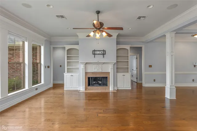 a view of a livingroom with a fireplace a chandelier fan and windows