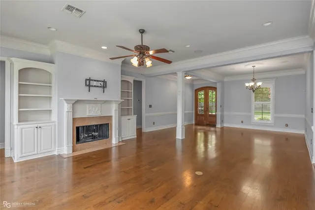 an empty room with wooden floor fireplace and a window