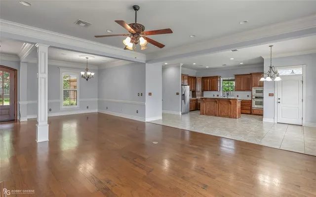an empty room with wooden floor and a kitchen