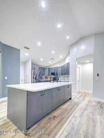 a room with kitchen island sink and cabinets