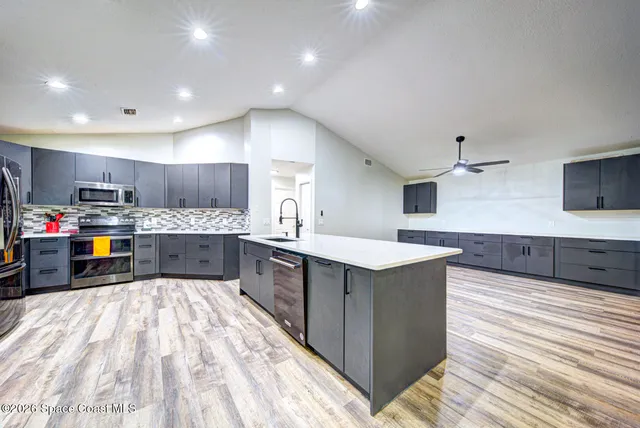 a large kitchen with stainless steel appliances kitchen island a large counter top a sink a stove and a refrigerator