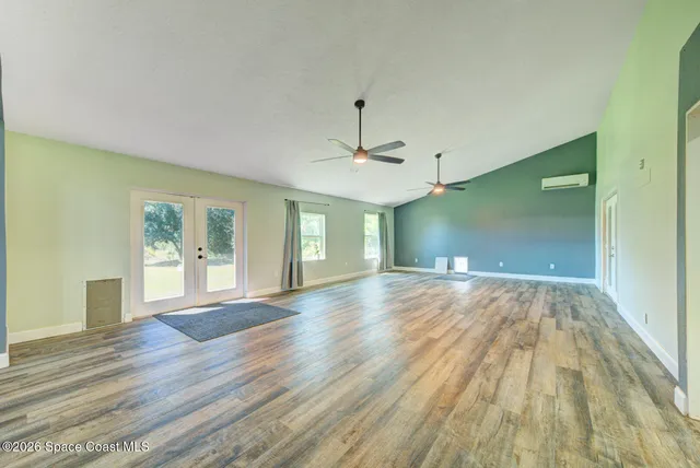 a view of an empty room with wooden floor and windows
