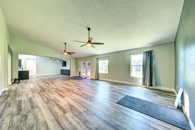a view of empty room with wooden floor and fan