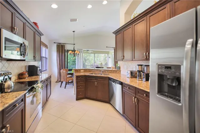 a open kitchen with stainless steel appliances granite countertop a stove top oven a sink dishwasher a dining table and chairs with wooden floor