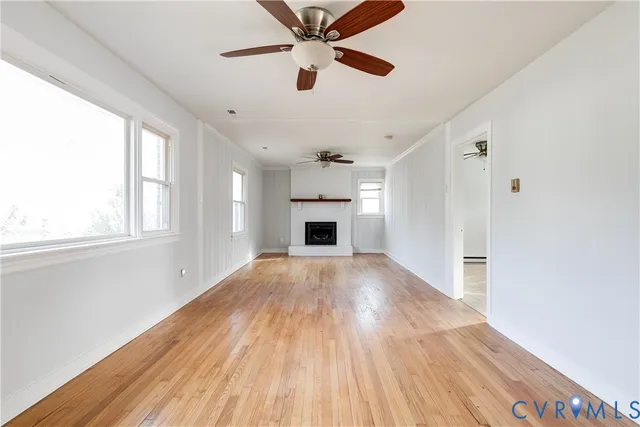 a view of empty room with a fireplace and wooden floor