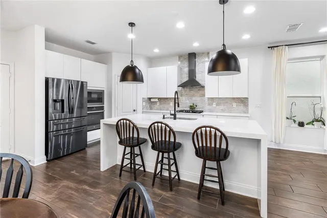 a kitchen with stainless steel appliances kitchen island granite countertop a refrigerator a stove a microwave oven a sink with island chairs and wooden floor