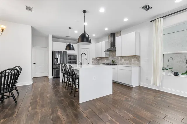 a kitchen with stainless steel appliances a sink a stove a refrigerator cabinets and wooden floor