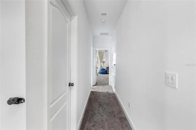 a view of a hallway with wooden floor and a bathroom