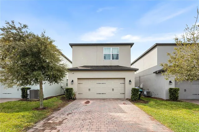 a front view of a house with a yard garage and a tree