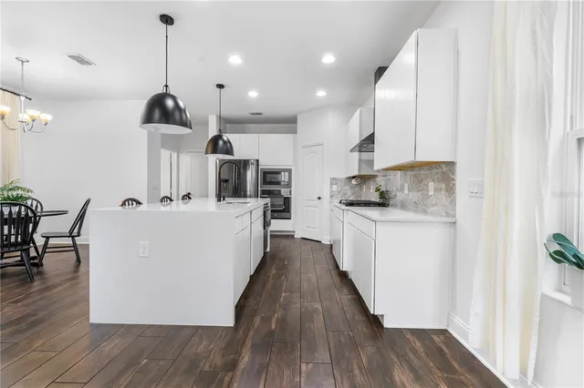 a view of a kitchen with kitchen island stainless steel appliances a center island and a wooden floor