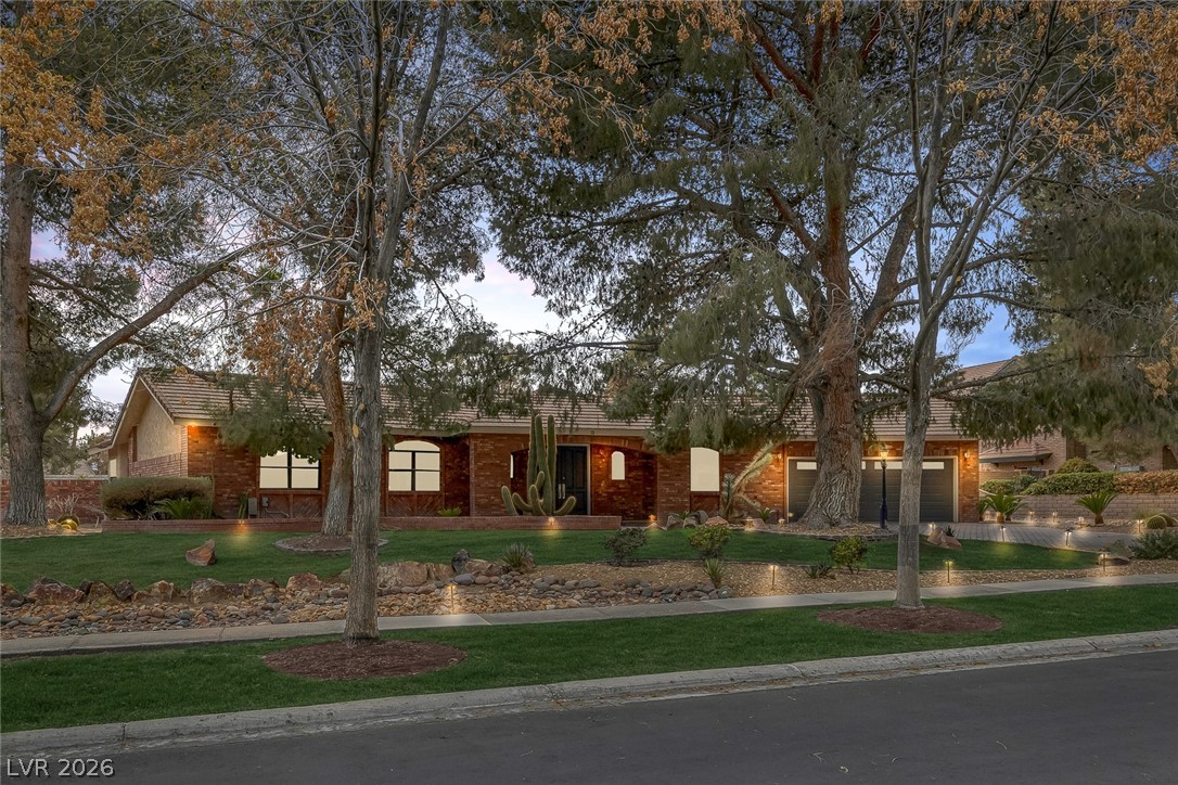 View of front of property with curved driveway, a front yard, and a garage