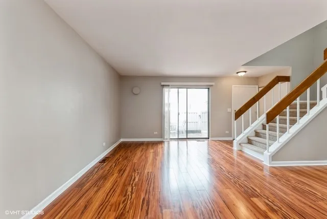 a view of an empty room with wooden floor and fan