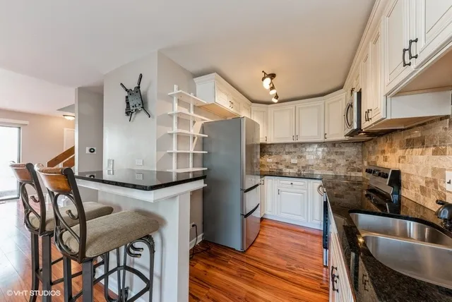 a kitchen with stainless steel appliances granite countertop a table chairs in it and wooden floors