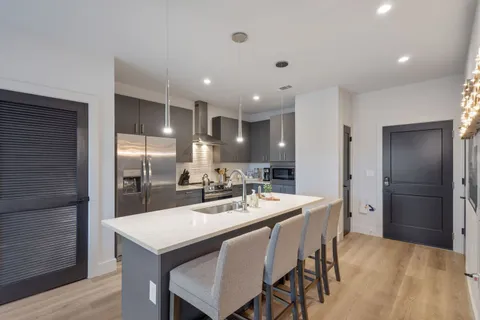 a kitchen with a dining table cabinets appliances and wooden floor
