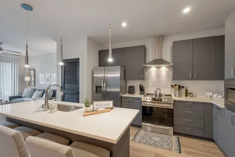 a kitchen with stainless steel appliances kitchen island granite countertop a sink a stove and refrigerator