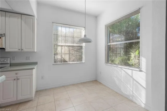 a view of a kitchen with white cabinets and a window