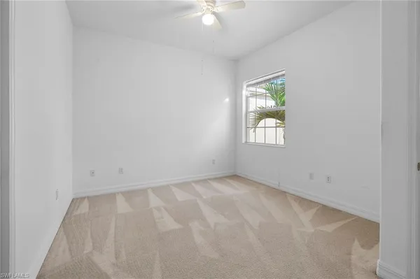 an empty room with a window and a ceiling fan