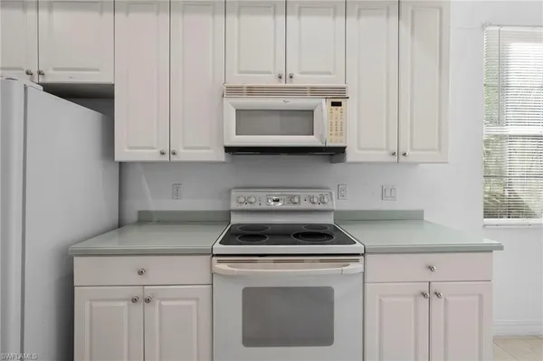 a kitchen with white cabinets and white appliances