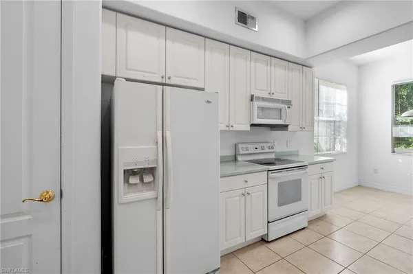 a kitchen with white cabinets and white appliances