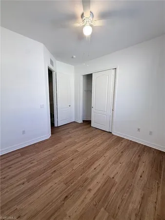 an empty room with wooden floor and fan