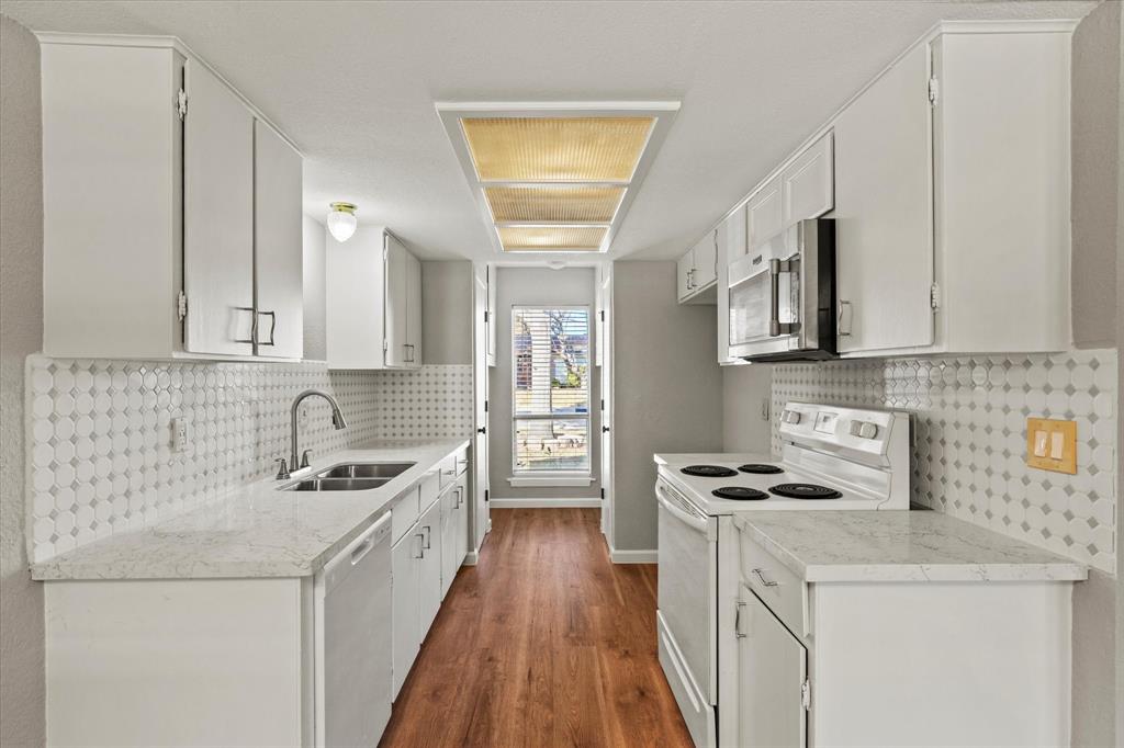 900 Wandering Way Drive Allen, TX 75002 - Photo 16 of 35 a kitchen with stainless steel appliances a white stove top oven a sink a refrigerator white cabinets and wooden floor