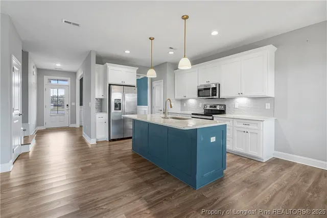 a large kitchen with stainless steel appliances kitchen island a stove a refrigerator a sink dishwasher a oven and a dining table with wooden floor