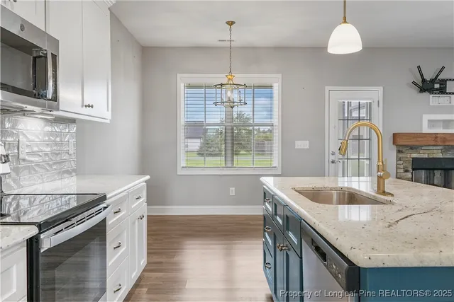 a kitchen with stainless steel appliances granite countertop a sink a stove and a wooden floors