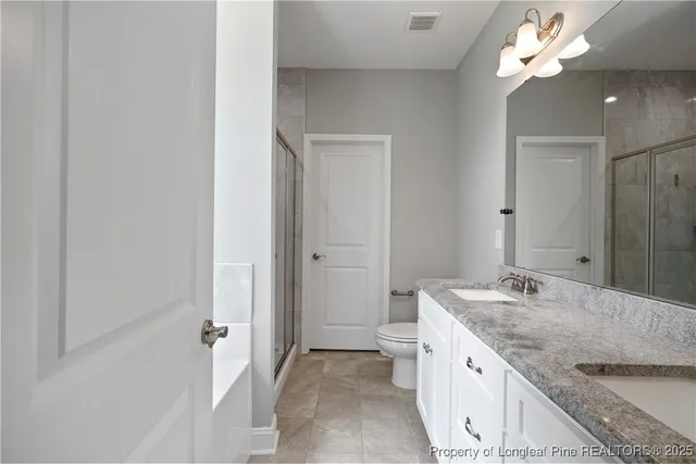 a bathroom with a granite countertop double vanity sink and a mirror