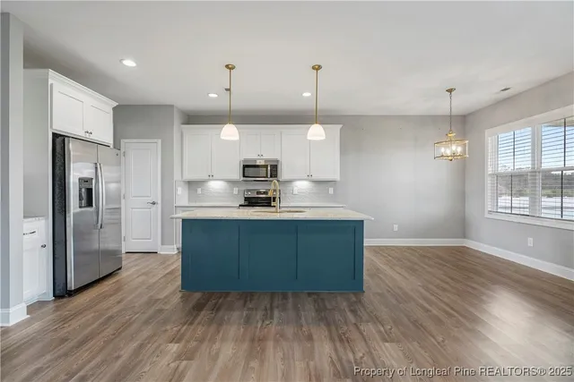 a kitchen with stainless steel appliances granite countertop a refrigerator a sink dishwasher a stove and white countertops with wooden floor