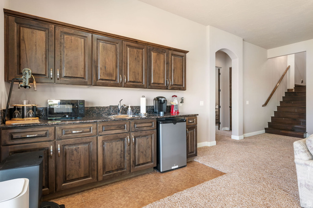 2376 Stone Crest Circle St. George, UT 84790 - Photo 33 of 61 Kitchen featuring dark wood finish cabinets, arched walkways, stainless steel refrigerator, black microwave, and dark stone counters