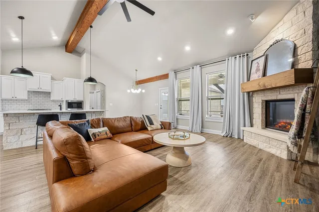 a open kitchen with stainless steel appliances granite countertop a stove a refrigerator a sink dishwasher and a dining table with wooden floor