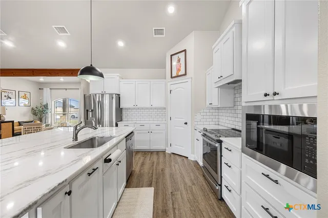 a kitchen with granite countertop a sink and a wooden floor