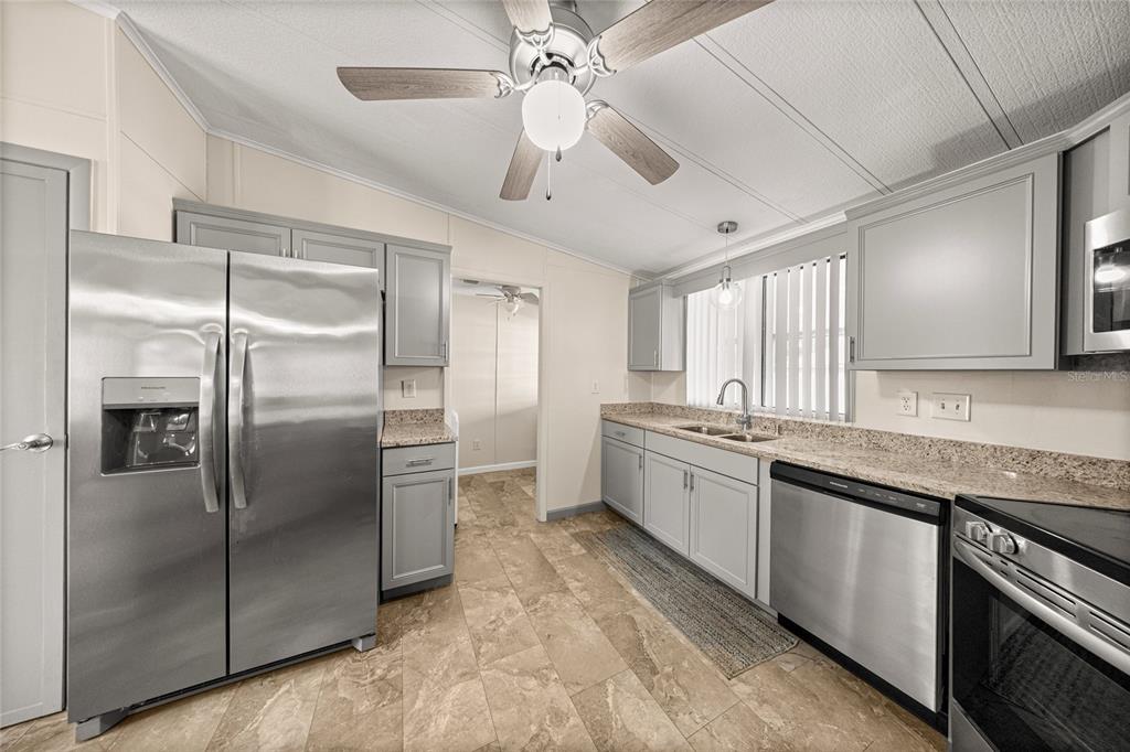 712 Devon Drive Lady Lake, FL 32159 - Photo 12 of 31 a large kitchen with stainless steel appliances granite countertop a refrigerator and a sink