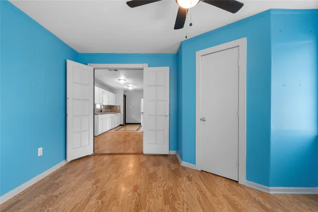 a view of empty room with wooden floor and ceiling fan