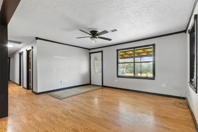 an empty room with windows and ceiling fan