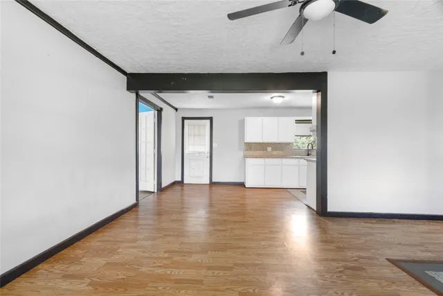 a view of an empty room with a window and wooden floor