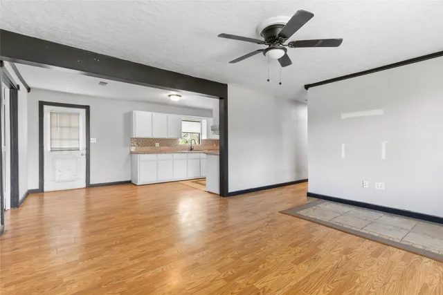 a view of an empty room with window and wooden floor