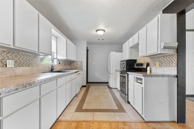 a kitchen with granite countertop white cabinets sink and stainless steel appliances