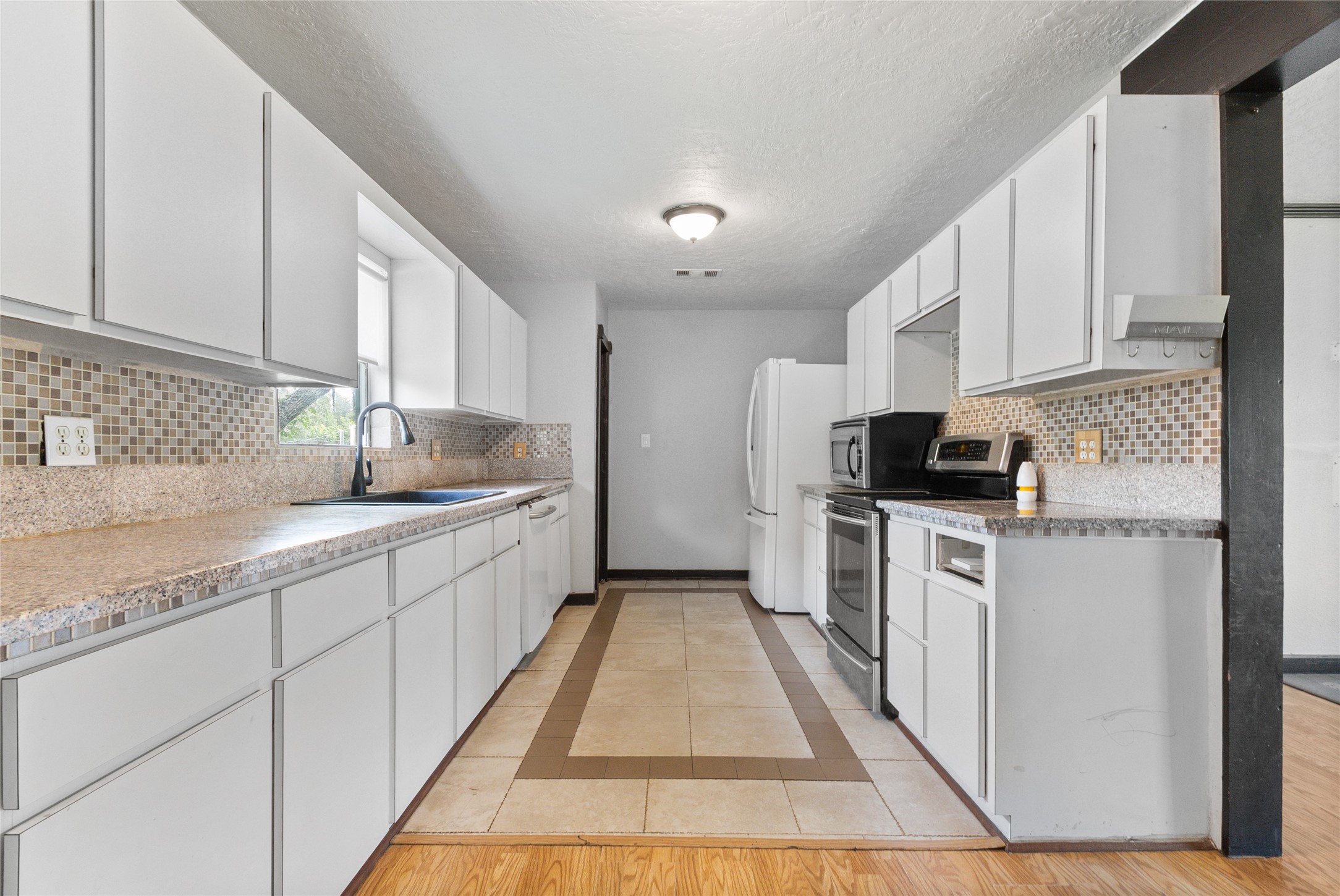 10315 North Walker Road Cleveland, TX 77328 - Photo 9 of 27 a kitchen with granite countertop white cabinets sink and stainless steel appliances