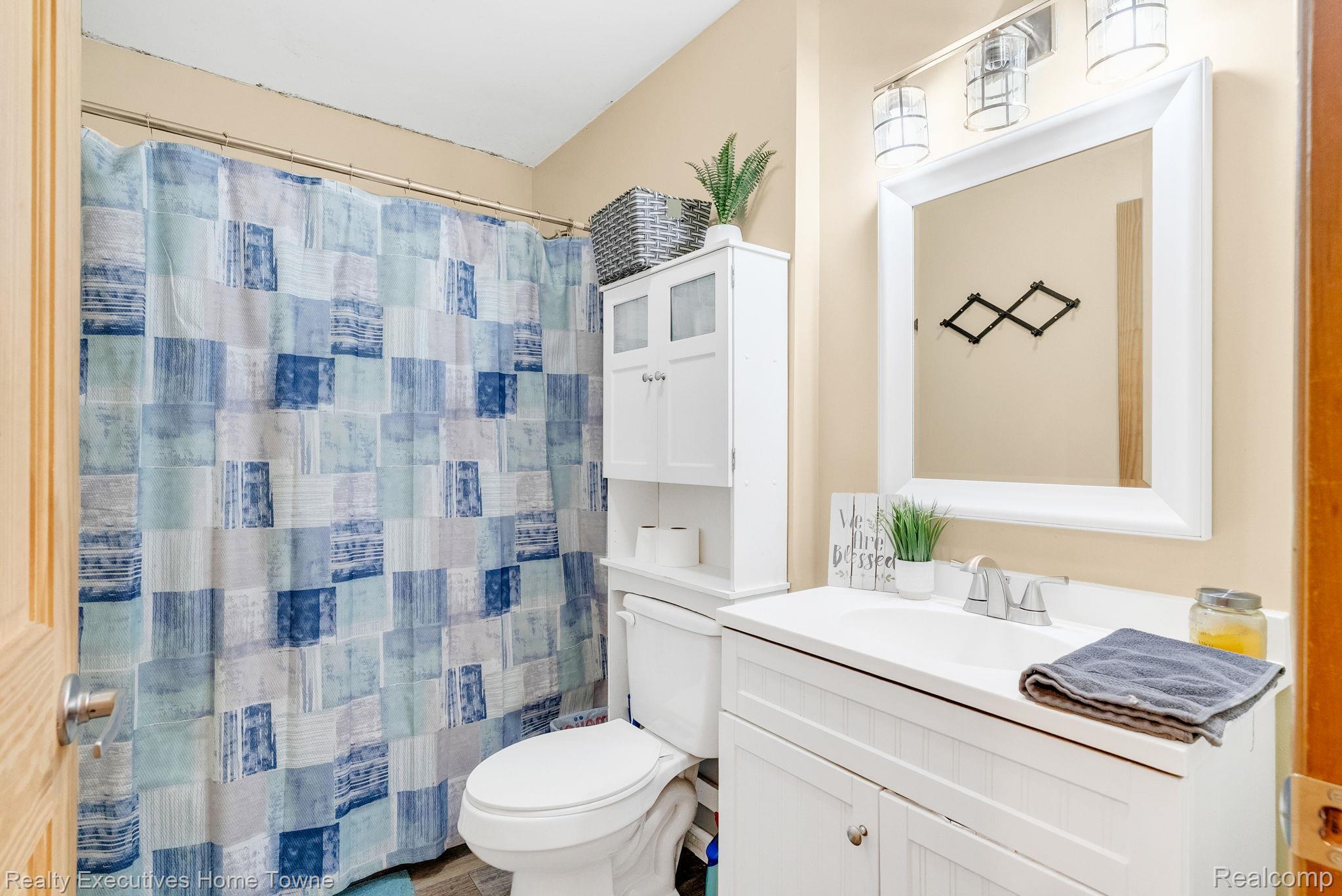 6560 Roach Road Lexington, MI 48450 - Photo 24 of 36 Bathroom featuring a white vanity with an integrated sink, a large framed mirror, and a three-light fixture