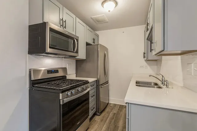a kitchen with stainless steel appliances a sink a stove a microwave and cabinets