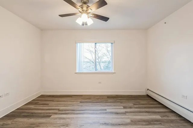 an empty room with wooden floor chandelier fan and window