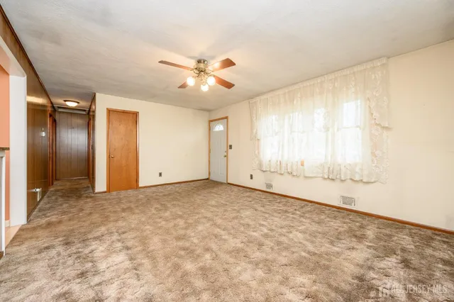 an empty room with a ceiling fan and a window