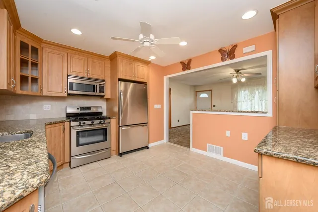 a kitchen with stainless steel appliances granite countertop a refrigerator a stove and a sink with wooden floor